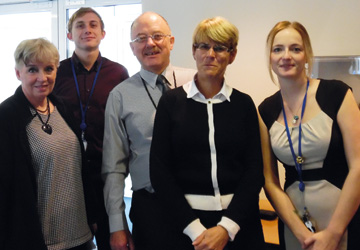 5 business people standing and smiling at the camera