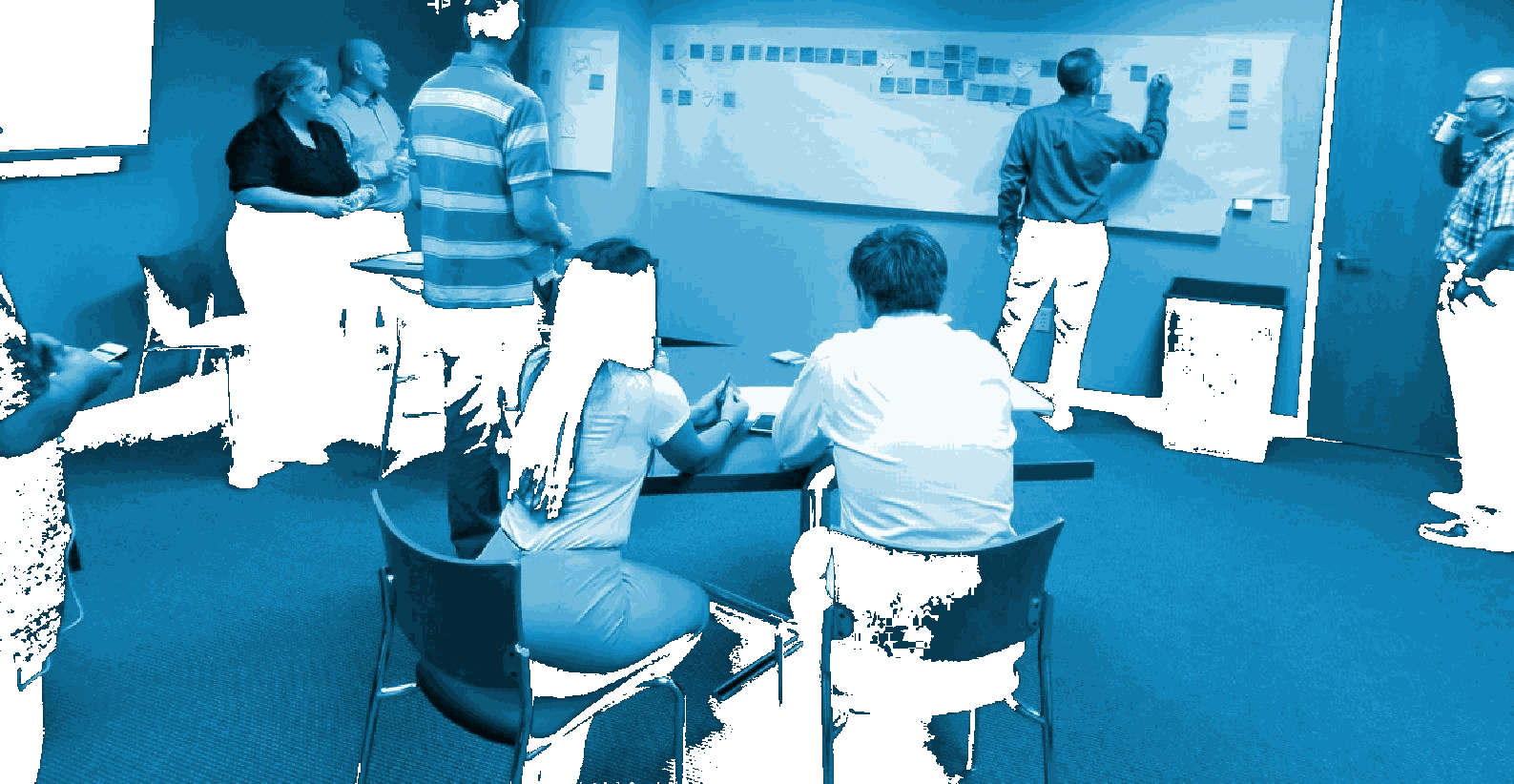 Team taking part in a process mapping workshop around a whiteboard
